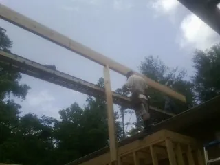 Carpenter setting a ridge beam over a new addition frame — Ice Dam Removal by Roofing Brothers in Quinlan