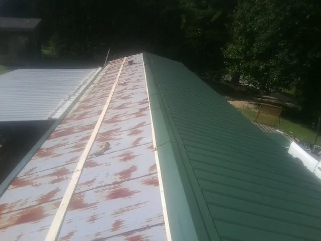 Old rusted panels beside newly installed green metal roofing — Wind Damage Roof Repair by Roofing Brothers in Quinlan