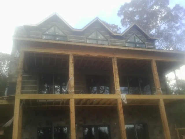 Dormers and porch framing on a large log home under construction — Roof Coating work by our crew in Quinlan