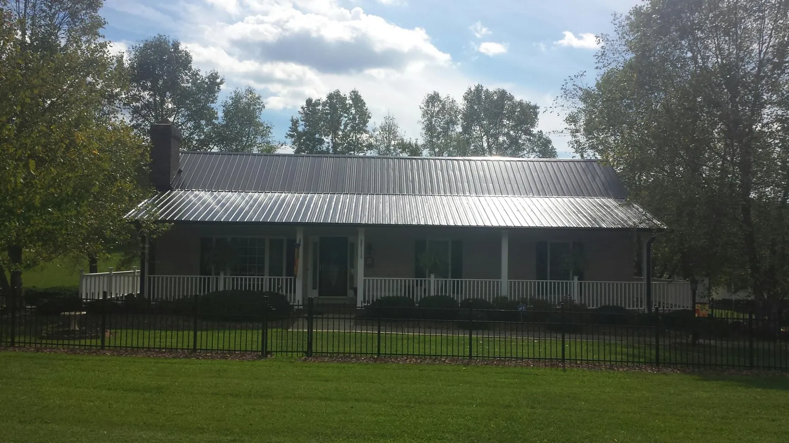 Gray metal roof on a brick ranch with a full width front porch — Gutter Guard Installation work by our crew in Quinlan