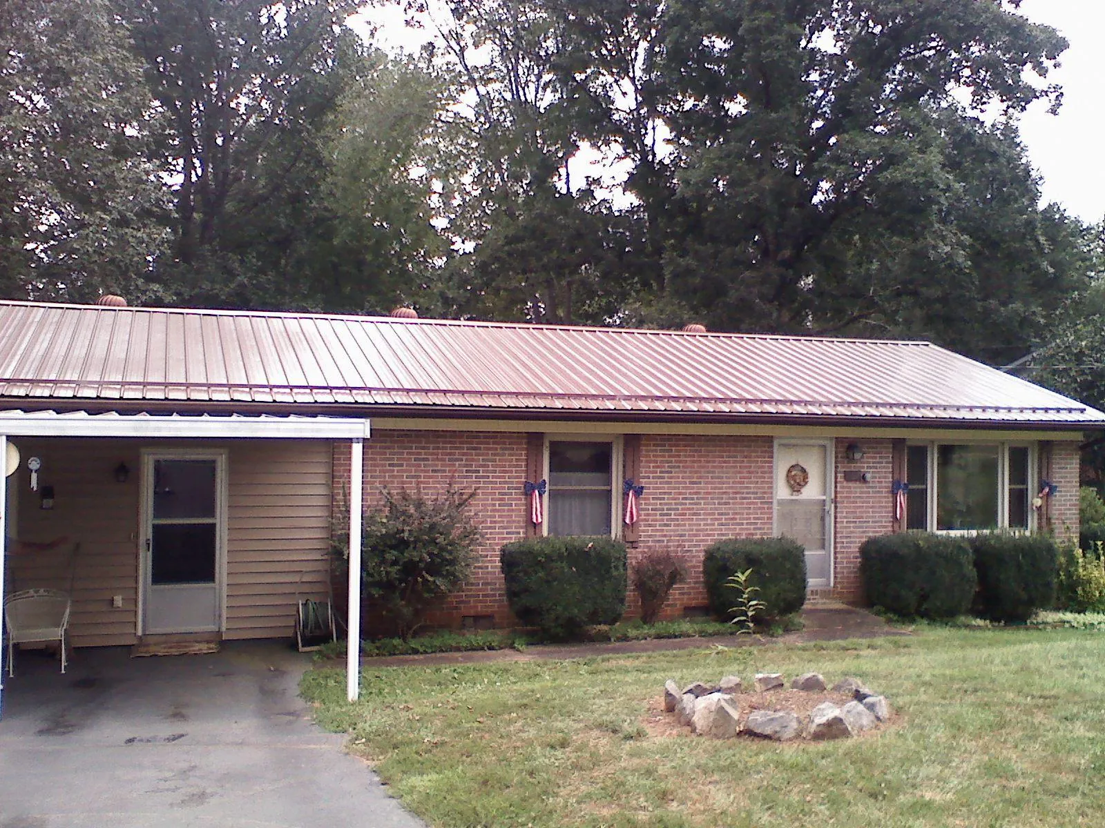 Bronze metal roof and carport on a brick ranch home — Roof Repair work by our crew in Quinlan