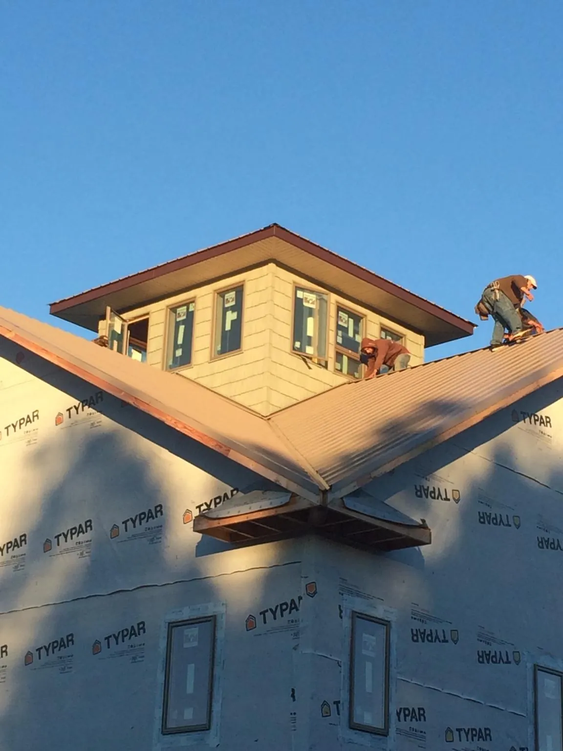 Roofers working around a rooftop cupola on a new metal roof at sunset — Roof Waterproofing in Quinlan by Roofing Brothers